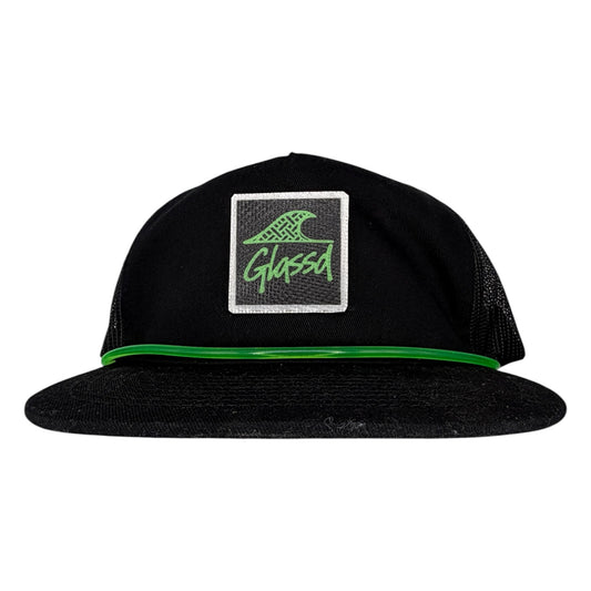The Laminate, black GLASSD hat with handmade fiberglass patch and green surfboard leash over the bill