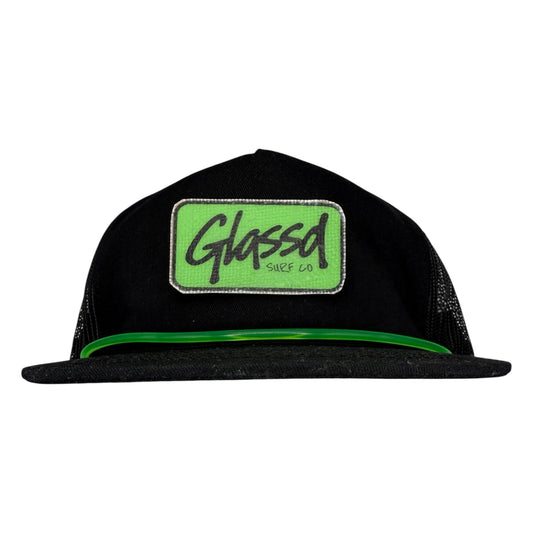 The Shaper, black GLASSD hat with handmade fiberglass patch and green surfboard leash over the bill