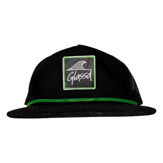 The Stringer, black GLASSD hat with handmade fiberglass patch and green surfboard leash over the bill